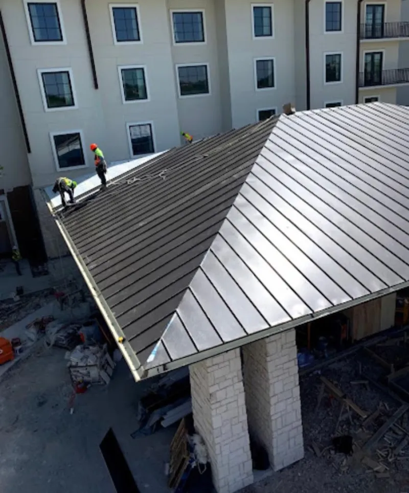 Crew installing standing seam metal roof panels on a commercial project in Emmett